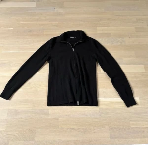 Stickad zip tröja - Riktigt schysst stickad zip tröja från J.lindeberg. Storleken är M och är i materialet Merino ull. Kontakta mig vid fler frågor!