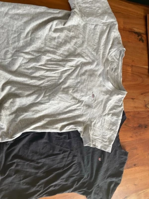 2-pack GANT t-shirts grå & svart - Två klassiska t-shirts från GANT i färgerna grå och svart. Båda har rund halsringning och liten broderad GANT-logga på bröstet. Tillverkade i mjuk bomull och har en normal passform med korta ärmar. Perfekta till jeans eller shorts.