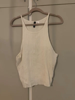 Ribbad vit linnetopp från H&M - Säljer en vit ribbad linnetopp från H&M i storlek XL. Toppen har smala axelband och rund halsringning, perfekt för en avslappnad och trendig look. Är aldrig använt, dock är de miss i produktion förmodligen då svart tråd verkar ha använts på 2 ställen (se bilder) absolut inget som sticker ut och märks knappt. I övrigt super fint skick!