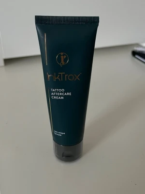 InkTrox Tattoo Aftercare Cream - heltny och oöppnad. -  En vårdande kräm speciellt framtagen för tatueringar. Hjälper huden att aterhämta sig, återfuktar på djupet och skyddar färgerna under läkningsprocessen. Innehåller bland annat aloe vera, panthenol, kokosolja och kamomill som lugnar och mjukgör huden. Perfekt för både nya och äldre tatueringar. Skick: 100% ny, förpackningen är aldrig öppnad. Tillverkad i Polen..
