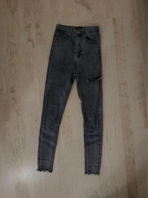Blå/grå skinny jeans med slitning PrettyLittleThing - Säljer ett par blå/grå skinny jeans med hög midja. Jeansen har en sliten detalj vid ena knät och klassiska fem fickor. 