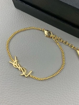 Guldfärgat armband - Snyggt och stilrent armband i guldfärgad metall. Armbandet har en tunn kedja och ett YSL-logo-hänge i mitten.🤍