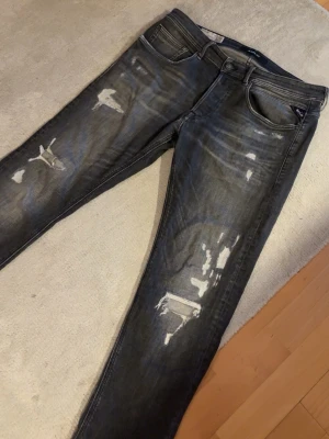 Replay jeans Willbi - Säljer ett par svarta/gråa replay jeans med snygg slitage design på byxorna