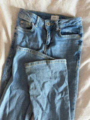 Ljusblå jeans  - Säljer ett par ljusblå jeans från grunt med klassisk femficksdesign och raka lätt utsvängda ben ner till. Jeansen har normal midja, bälteshällor och dragkedja 