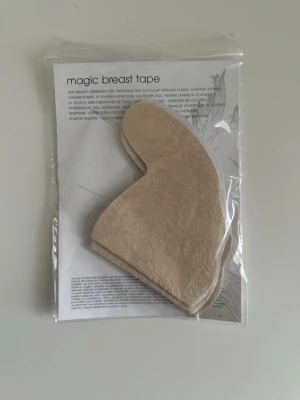 Magic breast tape i beige spets - NY i förpackning  - Helt NYA Magic breast tape från Lindex i beige med vacker spetsstruktur. Tejpen är formad för att ge stöd och lyft utan bh och passar perfekt under plagg med öppen rygg eller djup urringning. Materialet är mjukt och flexibelt för att sitta bekvämt mot huden. Nya i förpackning. 