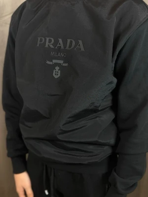 Svart hoodie  - Snygg svart hoodie . Hoodien har en klassisk passform med långa ärmar och ribbade muddar. Tillverkad i mjukt material som känns skönt mot huden. Perfekt för dig som gillar exklusiva streetwear-plagg.