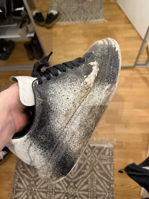Svarta och vita sneakers Från Alexander Mqueen - Sneakers i svart och vitt med kraftig sula och svarta skosnören. Skon har en låg silhuett och är tillverkad i läder. Färgen är gradient från svart till vitt, med svart på ovandelen och vit på hälen och sulan.
