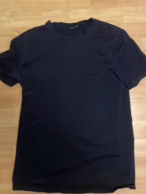 Marinblå basic t-shirt - En enkel marinblå t-shirt med rund hals och korta ärmar. Perfekt till jeans eller shorts för en clean och stilren look. Tillverkad i mjukt bomullsmaterial som känns skönt mot huden.