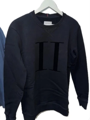 Svart sweatshirt från Les Deux - Hej! Snygg svart sweatshirt från Les Deux med stort svart II-tryck på bröstet. Tröjan har rund halsringning, ribbade muddar vid ärmslut och nederkant samt en klassisk, avslappnad passform. Perfekt för en stilren och enkel look. Den kostar 1399kr hos Zalando länk: Fantastisk produkt från Zalando: https://www.zalando.se/les-deux-encore-sweatshirt-black-lep22s065-q11.html. Jag säljer min för 549kr 