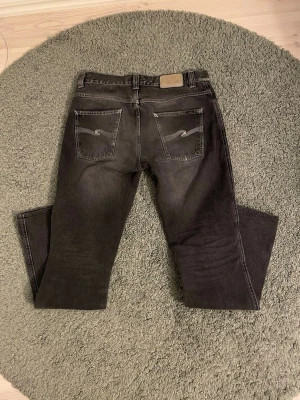 Mörkgrå nudie jeans - Säljer ett par feta mörkgrå jeans från Nudie Jeans W31 och L34 med raka ben, perfekt för en mer avslappnad look⭐️skriv i dm om du vill ha bild på defekter eller andra funderingar👑