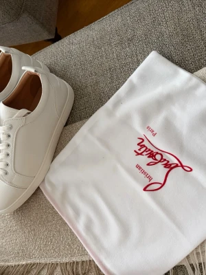 Vita låga sneakers från Christian Louboutin - Stilrena vita sneakers från Christian Louboutin i slätt läder med klassisk låg siluett. Skorna har vita snören, diskreta sömmar och en lyxig känsla med beige innersula. 