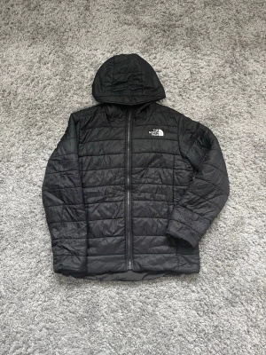 Svart pufferjacka från The North Face - Säljer en svart pufferjacka från The North Face med huva och dragkedja framtill i storlek S, säljs för 400kr!