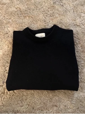 Svart merinoulltröja från Vailent - Klassisk svart stickad tröja från Vailent i mjuk merinoull. Tröjan har rund halsringning och ribbade muddar. Perfekt basplagg för lager på lager och enkel att matcha med allt i garderoben.