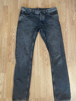 Svarta raka jeans med kontrastsömmar - Säljer ett par svarta jeans med raka ben. Jeansen har klassisk femficksdesign och normal midja. Materialet är denim i bomull. Perfekta för en avslappnad och stilren look. Storlek W32 L34. Tveka inte att höra av dig vid funderingar. 
