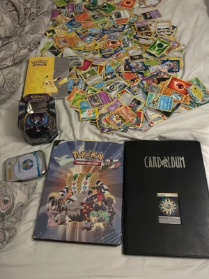 Stort Pokémonkort- och figurpaket - Säljer ett stort paket med Pokémonkort, två samlaralbum, plåtlådor och massor av små Pokémonfigurer. Korten är i olika färger och motiv, och albumen har snygga omslag. Perfekt för samlare eller dig som vill bygga din egen samling! Dom flesta är common cards men det är mycket kort som fan. Pärmarna är fulla oxå så det kanske är runt 800-1000 kort från alla år, från 1996-2025
