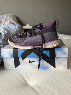 Under armour Curry basketskor - Säljer ett par snygga sneakers från Under Armour Curry-serien i lila och svart med mesh- och syntetmaterial. Skorna har en sportig design med SC-logga på sidan och lila detaljer runt kragen. Perfekta för dig som gillar basketstil och vill sticka ut.