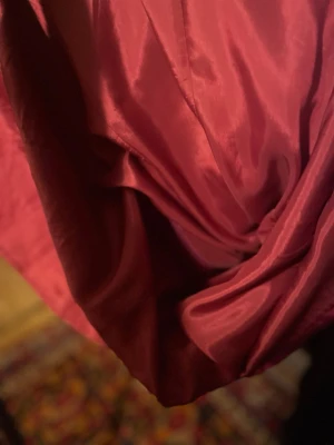 Röd omlottklänning i satin - Säljer en röd omlottklänning i glansigt satinmaterial. Klänningen har en elegant omlottdesign och en mjuk, följsam känsla. Perfekt för dig som vill ha en stilren och trendig look.