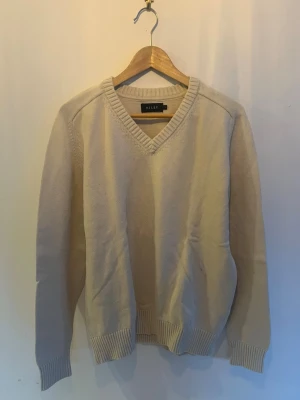 V-ringad stickad tröja Riley - Créme färgad stickad tröja från Riley i storlek L, i princip oanvänd.
