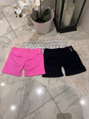 2-pack cykelshorts från DYFNE - Två par cykelshorts från DYFNE, ett par i knallrosa och ett par i svart. Båda har hög midja och är tillverkade i ett stretchigt material som passar perfekt för träning. Loggan sitter diskret på linningen framtill. ( små i storlek , passar M också ) annars är storleken på båda L ångrade mig helt så väljer sälja vidare. PAKETPRIS 