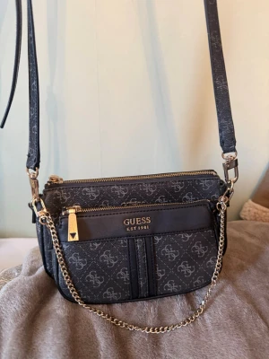 Väska - Väska från Guess som kan användas på flera sätt. Den går att plocka isär så du får en miniväska, eller använd som en axelrems-väska. Köpt från Zalando. Mycket fint skick.