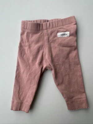 Rosa leggings från Newbie - Söta rosa leggings från Newbie i mjuk bomull med resår i midjan och dekorativt vågig kant vid benslut. Perfekta för en avslappnad och bekväm stil.