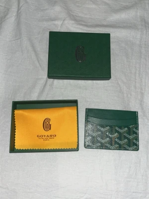 G-plånbok - Snygg och stilren i färgen grön med deras ikoniska mönster. Plånboken har flera kortfack och är tillverkad i skinn med tryckt logga framtill. Perfekt för dig som vill ha något exklusivt och smidigt i fickan.  