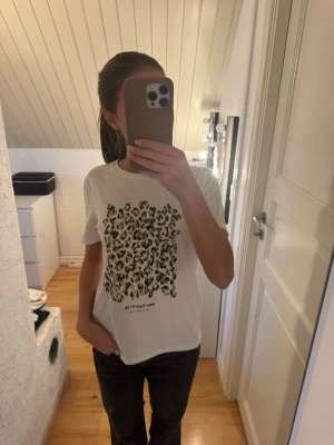 Vit t-shirt med leopardmönster - Snygg vit t-shirt med stort leopardmönster framtill. T-shirten har klassisk passform och rund halsringning. 