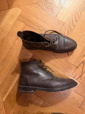 Tiger herrsko med snörning - Snygga bruna stövletter i äkta läder med klassisk snörning och låg klack. Skorna har en stilren design med rundad tå och robust sula, perfekta för dig som gillar en tidlös look. Passar till både jeans och chinos.