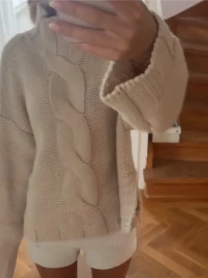 Beige kabelstickad tröja - Beige kabelstickad tröja med hög krage och vida ärmar. Tröjan har ett grovt stickat mönster med en bred kabeldetalj framtill. Perfekt för lager på lager, slutsåld på Zaras hemsida💞💞