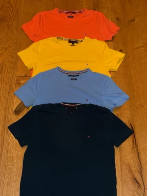 Fyrpack Tommy Hilfiger t-shirts - Fyra klassiska t-shirts från Tommy Hilfiger i olika färger: orange, gul, ljusblå och marinblå. Perfekta basplagg i mjuk organisk bomull. Passformen är slim fit i strl M. Köp 1 t-shirt för 200kr. Alla för 650kr. 
