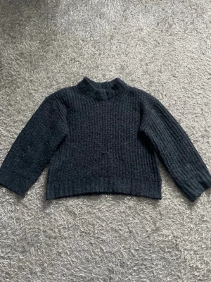 Mörkblå stickad tröja från lager 157 - Mysig mörkblå stickad tröja från lager 157 med högre hals och ribbade muddar. Tröjan har ett diskret rutmönster i stickningen och är perfekt för kyliga dagar. Passar dig som gillar enkel och stilren design.