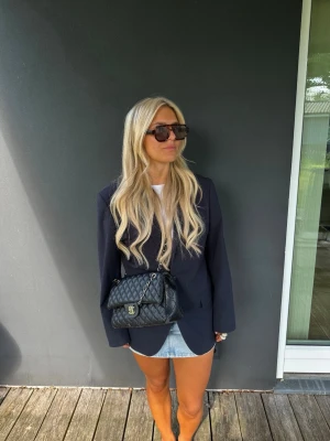 Mörkblå kavaj från Lindbergh - Mörkblå kavaj från Lindbergh med klassisk passform och blankt foder. Enkel att matcha med både jeans och kjol. Mått från axel ner till kant 75cm. Är som en medium skulle jag säga.