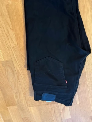  Levi's jeans man  - Säljer ett par svarta jeans från Levi's med klassisk rak passform och fem fickor. Jeansen har dragkedjegylf och nitar vid fickorna. Perfekta till en avslappnad stil och funkar året runt.