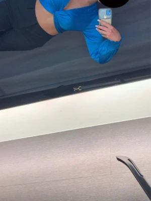 Blå croppad omlottopp med v-ringning - Snygg blå croppad omlottopp med v-ringning och långa puffärmar. Toppen har en twistad detalj framtill och är tillverkad i ett lätt, mjukt material som ger en skön känsla. Perfekt för dig som vill sticka ut med färg och trendig design.