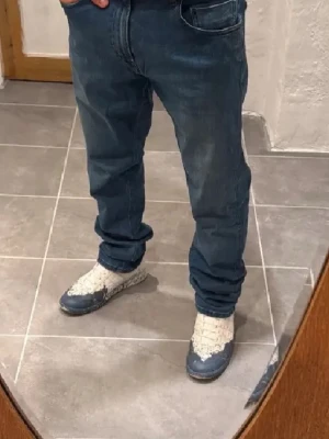 Blå jeans från replay - Säljer ett par klassiska blå jeans från Nudie Jeans med rak passform och fem fickor. Jeansen har en snygg tvättad look och detaljerad söm på bakfickan. Perfekta till vardagsstilen och tillverkade i mjuk denim.