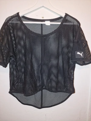 Svart mesh t-shirt från Puma - Svart topp i mesh-design, snyggt att ha över sportbh:n. S för avslappnad passform M för tight passform.