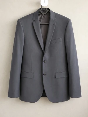 Grå kavaj Tiger of Sweden - Stilren grå kavaj från Tiger of Sweden i modellen Norden BZ. Klassisk passform med två knappar, tre fickor framtill och slät finish. Materialblandning av polyester, ull och elastan för en bekväm känsla. Perfekt för en dressad look.