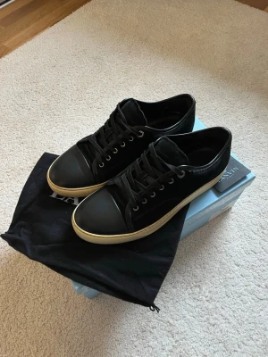 Lanvin Paris sneakers – Strl 41 – Mycket fint skick - Säljer ett par stilrena Lanvin Paris sneakers i svart med vit sula. Skorna är i väldigt fint skick och sparsamt använda. Perfekta både till vardags och lite mer uppklädda outfits. PRIS= 1999kr * Märke: Lanvin Paris * Storlek: 41 * Färg: Svart * Skick: Väldigt bra skick * Originalbox, dustbag och kort medföljer  Sulorna visar minimalt slitage och skorna är väl omhändertagna. Nypris betydligt högre. 