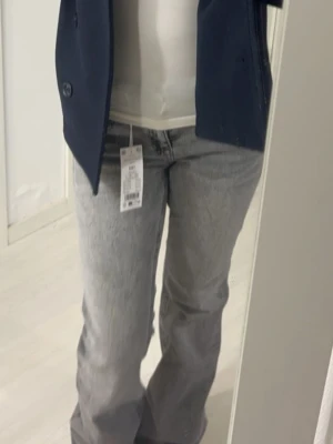 Grå bootcut jeans från Gina Tricot - Säljer ett par snygga grå bootcut jeans från Gina Tricot. Jeansen har en klassisk femficksmodell, hög midja och utsvängda ben. Materialet är mjukt denim med en tvättad look som ger en cool vintagekänsla. Perfekta till både sneakers och boots.