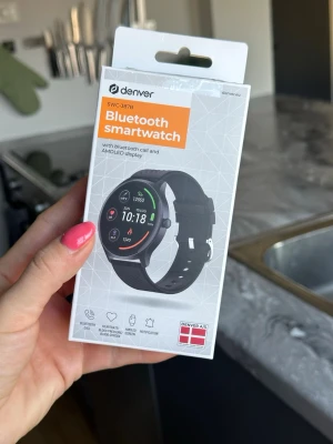 Denver SWC-387B Bluetooth Smartwatch - Snygg svart smartklocka från Denver, modell SWC-387B. Klockan har rund AMOLED-skärm, silikonarmband och stöd för Bluetooth-samtal, hjärtfrekvensmätning och notifikationer. Perfekt för dig som vill ha koll på både träning och vardag direkt på handleden. Endast använd 1 gång.