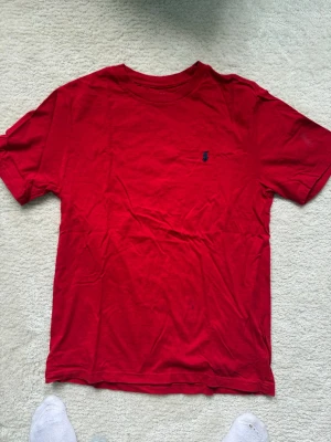 Röd t-shirt från Polo Ralph Lauren - Klassisk röd t-shirt från Polo Ralph Lauren med den ikoniska lilla broderade loggan på bröstet. T-shirten har rund halsringning och korta ärmar. Tillverkad i mjuk bomull som känns skön mot huden. Perfekt för en avslappnad och stilren look.