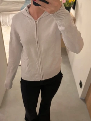 Ljusgrå hoodie med dragkedja - En enkel och stilren ljusgrå hoodie med dragkedja framtill och huva. Tröjan har ribbade muddar vid ärmslut och nederkant, samt en mjuk och bekväm passform🌸