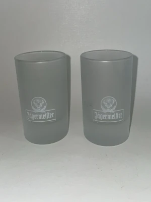 Jägermeister shotglas 2-pack större shot glas - 100kr för båda Två stycken frostat shotglas från Jägermeister med logga tryckt i vitt på framsidan. Glasen har en cylindrisk form och är perfekta för shots eller små drinkar. Snygg design för dig som gillar Jägermeister eller vill ha coola glas till festen.