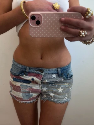 Lågmidjade Usa shorts - Såå fina  slitna lågmidjade vintage jeansshorts med usa flagga! midjemått rakt över: 39. Jag är 168 och det är mina bilder, köp via köp nu direkt eller Swish, kvar tills markerad som såld 💖 