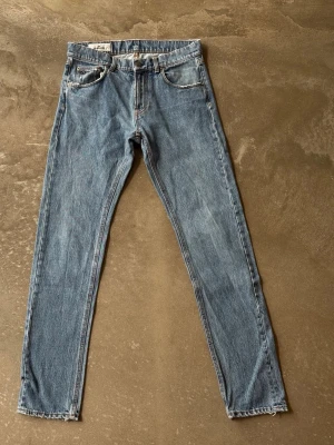 J.Lindeberg ”Tom” Straight Jeans – Clean Mid-Blue Denim (W30/L34) - Premiumdenim från skandinaviska J.Lindeberg. Modellen heter ”Tom” och har en modern, regular-rise midja och raka ben (straight fit). Den perfekta mellanblå tvätten som fungerar till allt, året om. Otroligt mjuk och lyxig denimkvalitet med fantastisk komfort. En riktigt stilren basbyxa för en minimalistisk garderob.