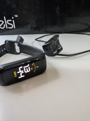 Svart Samsung Galaxy Fit2 smartklocka - Säljer en svart Samsung Galaxy Fit2 smartklocka med silikonarmband och färgdisplay. Klockan har en smal och sportig design, touchskärm och laddas via medföljande USB-laddare. Perfekt för att hålla koll på steg, puls och notiser direkt på handleden.