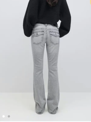 Grå bootcut jeans low petite - Snygga grå bootcut jeans med låg midja och klassiska fem fickor. Jeansen har en lätt tvättad look och markerade sömmar. Passformen är utsvängd nertill och modellen är petite, perfekt för dig som vill ha en trendig siluett.