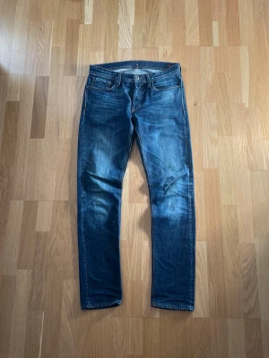 Mörkblå slim fit jeans - Snygga mörkblå straight fit jeans med klassisk femficksdesign och subtila slitningar på framsidan. Jeansen har normal midja och raka ben. Perfekta för en avslappnad och trendig look. Storlek 30/32