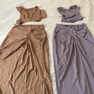 Långkjol i beige och lila med twist - Två snygga långkjolar i mjukt stretchigt material, en i beige och en i lila. Båda har en twistad detalj framtill som ger en cool draperad effekt. Perfekt för dig som gillar stilrena plagg med en twist. Säljes separat eller tillsammans! Passar 36-38 mycket bra skick använd 1 gång .199 kr/st vill du köpa båda gör jag paketpris 