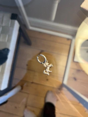 Maria Nilsdotter Silverfärgat örhänge med enhörning - Unikt örhänge i silverfärg med en liten enhörningsberlock. Ringen är enkel och smidig att bära, och enhörningen ger en lekfull och personlig touch till din stil. Perfekt för dig som gillar magiska detaljer och vill sticka ut lite extra.